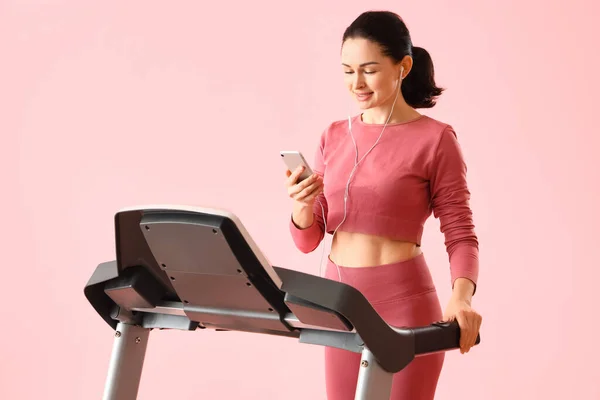 Beautiful Woman Mobile Phone Earphones Training Treadmill Pink Background — Stock Photo, Image