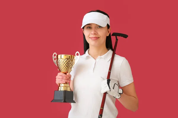 女性ゴルファー 赤い背景にゴールドカップ — ストック写真