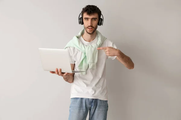 Νεαρός Άνδρας Ακουστικά Που Δείχνει Laptop Στο Φως Φόντο — Φωτογραφία Αρχείου