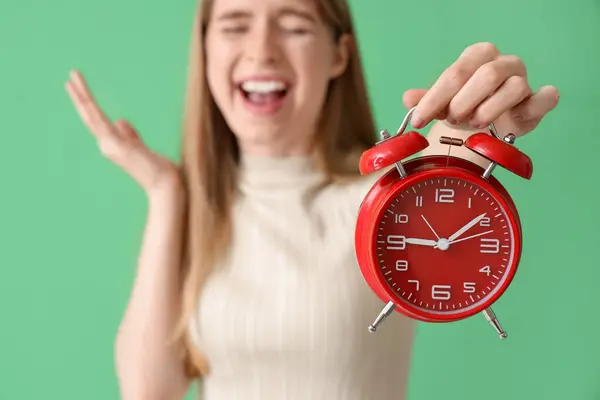 緑色の背景に目覚まし時計が付いているストレスを受けた若い女性 クローズアップ 締め切りのコンセプト — ストック写真