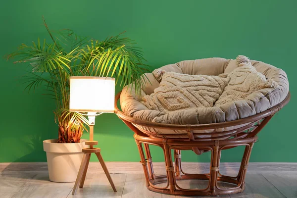 stock image Glowing lamp with armchair and palm tree near green wall in room