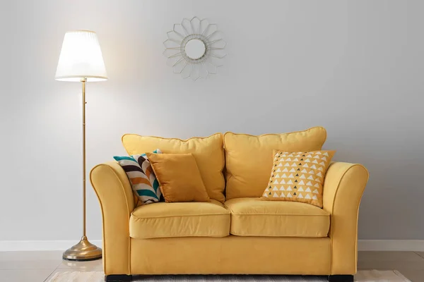 Lâmpada Brilhante Sofá Amarelo Com Almofadas Espelho Perto Parede Branca — Fotografia de Stock