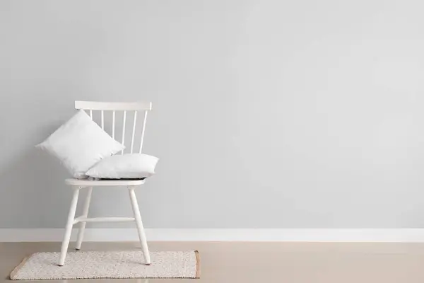 白い壁の近くの敷物の枕が付いている椅子 — ストック写真