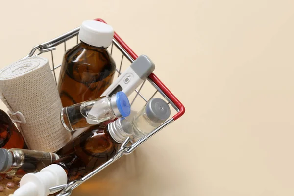 ベージュの背景に異なる薬とミニショッピングカート — ストック写真
