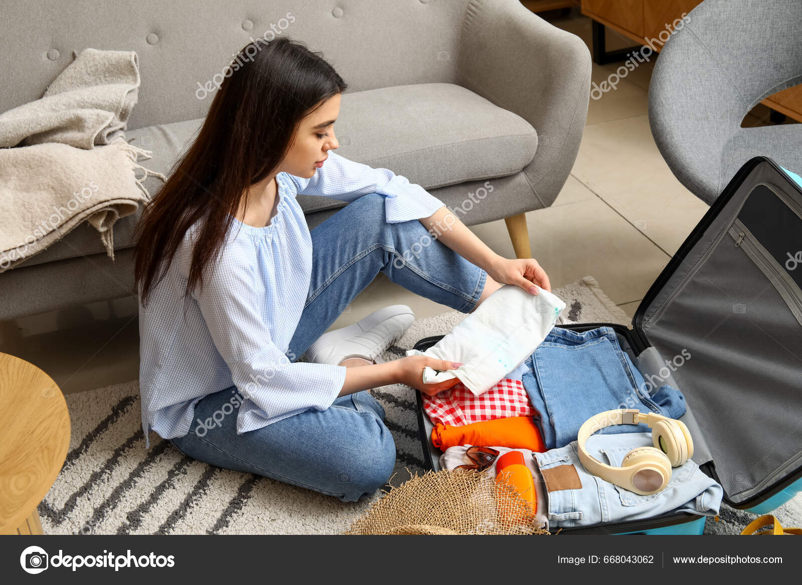 Young woman packing luggage in bedroom at home stock photo