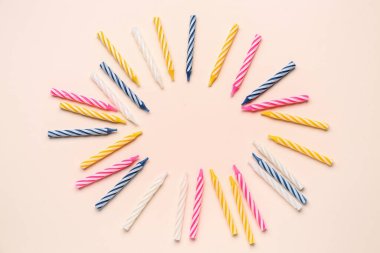 Pembe arkaplanda renkli doğum günü mumlarından yapılmış çerçeve