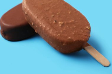 Çikolata kaplı lezzetli dondurma mavi arka planda, yakın planda.