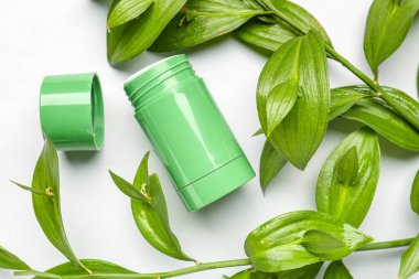 Deodorant şişesi ve beyaz arkaplanda yapraklar