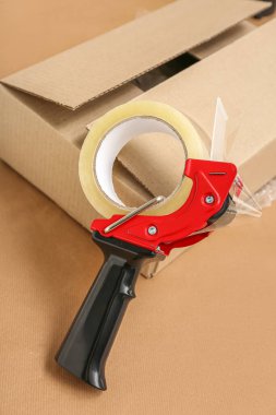 Bej arka planda bant dağıtıcısı ve karton kutu paketleniyor