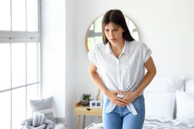 Yatak odasında regl sancısı çeken genç bir kadın.