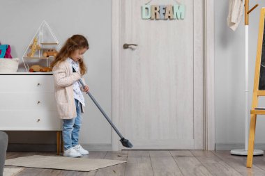 Evinde süpürgeyle yerleri süpüren sevimli küçük kız.