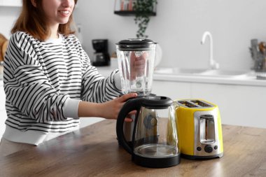 Mutfakta modern blenderi olan genç bir kadın.