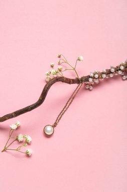 Güzel inci kolyeli ağaç dalı ve pembe arka planda çingene çiçekleri.