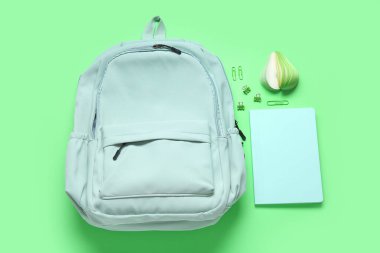 Yeşil arka planda farklı kırtasiyeye sahip şık okul çantası