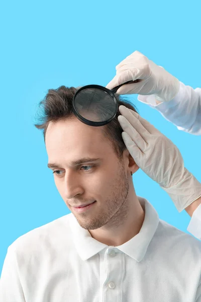Dokter Met Vergrootglas Onderzoek Van Jonge Man Haar Blauwe Achtergrond — Stockfoto
