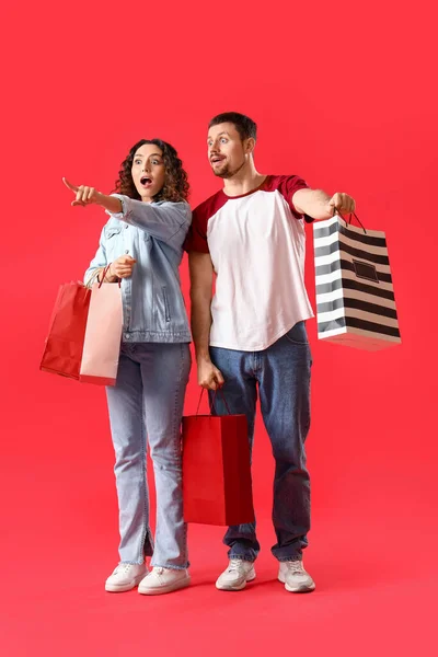 Kırmızı Arka Planda Alışveriş Torbaları Olan Genç Bir Çift — Stok fotoğraf