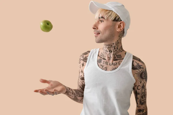 头戴米黄色背景苹果的纹身青年男子 — 图库照片