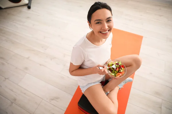 Αθλητική Νεαρή Γυναίκα Τρώει Σαλάτα Λαχανικών Στο Γυμναστήριο — Φωτογραφία Αρχείου