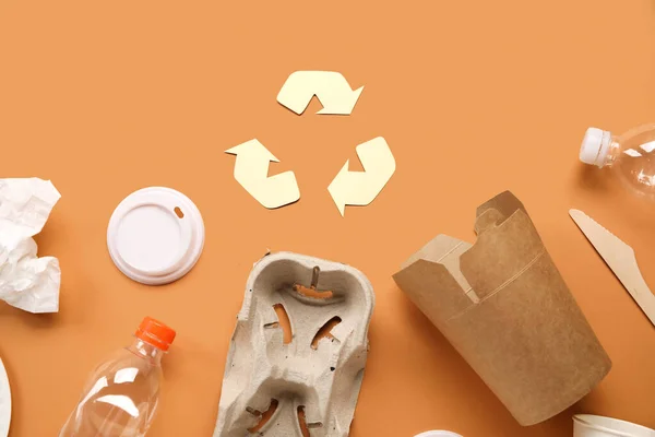Recycling sign with garbage on orange background