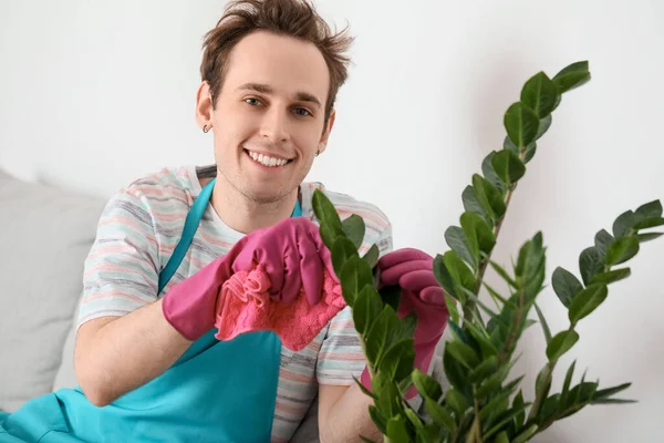 自宅で植物の葉を拭く若い男 — ストック写真