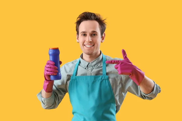 黄色の背景に洗剤を塗った若い男 — ストック写真