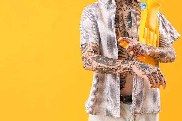 Tatuaż Mężczyzna Stosując Krem Ochrony Przeciwsłonecznej Żółtym Tle — Zdjęcie stockowe
