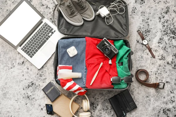 彩色地毯上装有男装 手提电脑和旅行配件的手提箱 — 图库照片