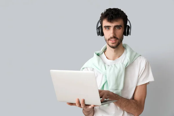 Молодий Чоловік Навушниках Працює Ноутбуком Світлому Фоні — стокове фото