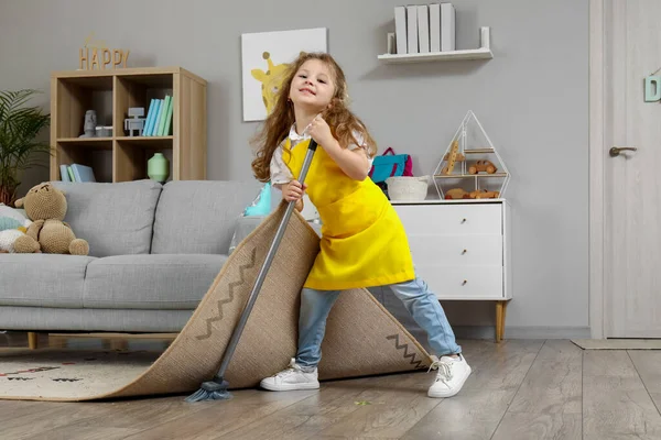 Graziosa Bambina Spazzare Pavimento Sotto Tappeto Con Scopa Casa — Foto Stock