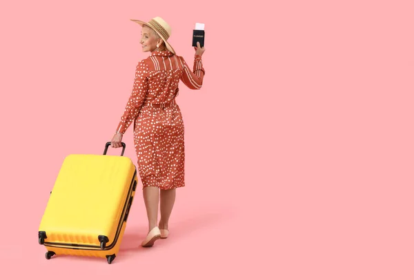 Зрелая Женщина Паспортом Чемоданом Розовом Фоне Вид Сзади — стоковое фото