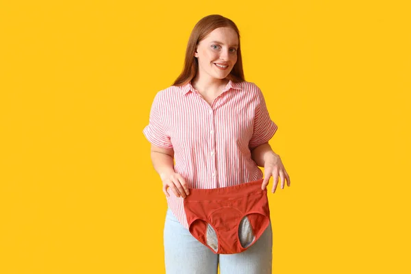 黄色の背景に月経パンティを持つ若い女性 — ストック写真