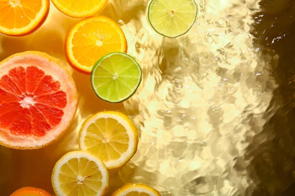 Diferentes Fatias Frutas Cítricas Água Fundo Amarelo — Fotografia de Stock