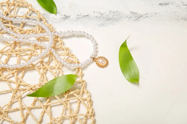 Wicker Mat Beautiful Pearl Necklace Plant Leaves Grunge White Background — Stock Photo, Image