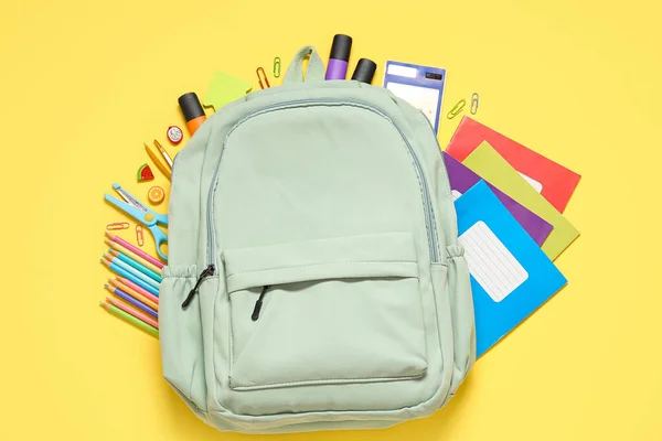 Πράσινη Σχολική Τσάντα Πλάτης Διαφορετικά Χαρτικά Κίτρινο Φόντο — Φωτογραφία Αρχείου