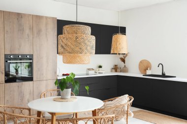 Işıl ışıl mutfağın içi fırın, yemek masası ve karanlık tezgahlarla dolu.