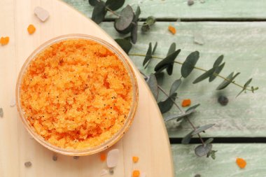 Composition with jar of body scrub and eucalyptus branches on color wooden background, closeup