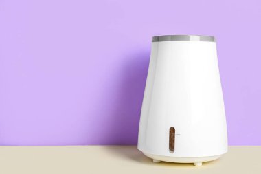 Modern nemlendirici, eflatun duvarın yanındaki masada.