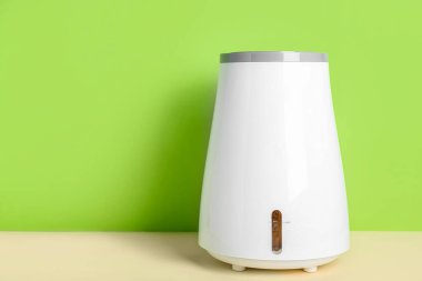 Modern nemlendirici yeşil duvarın yanındaki masada.