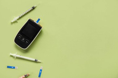 Yeşil zemin üzerinde şeritler ve şırıngalar olan glukometre. Diyabet kavramı