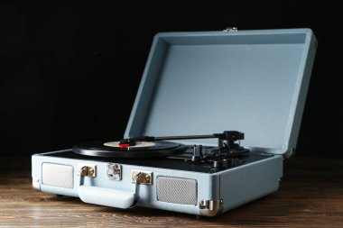 Koyu ahşap arka planda vinil diski olan kayıt çalar