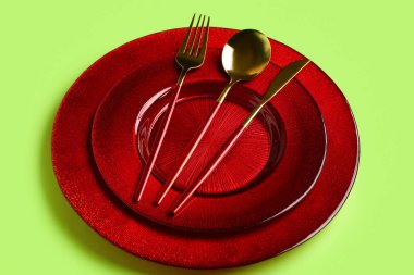 Yeşil zemin üzerinde temiz tabak ve çatal bıçak takımı olan masa ayarları