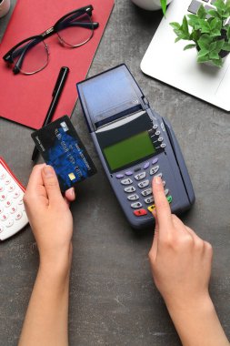 Siyah masada kredi kartıyla ödeme yapan bir kadın var.