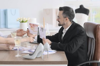 Erkek düğün organizatörü ofiste bir çiftle çalışıyor.