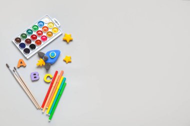 Kırtasiyeli plastikten yapılmış roket ve gri arkaplanda ahşap harfler