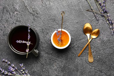 Tatlı lavantalı kase bal ve koyu arkaplanda bir fincan çay.