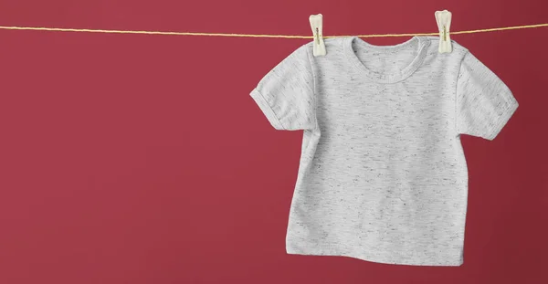婴儿T恤衫系在绳子上 衬托着彩色背景 设计横幅 — 图库照片
