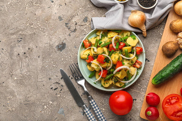 Тарелка вкусного картофельного салата с овощами и ингредиентами на фоне гранжа