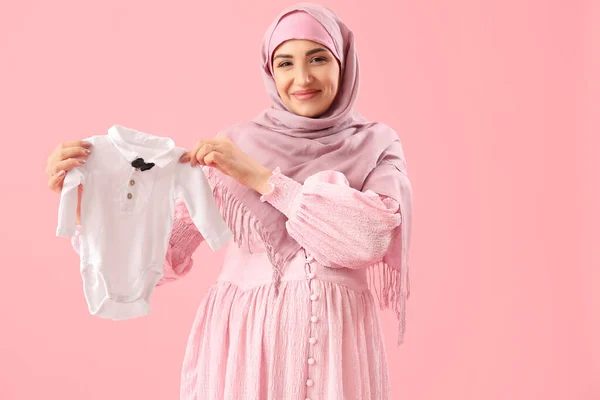 若いです妊娠中のイスラム教徒女性とともに赤ちゃんボディスーツ上のピンクの背景 — ストック写真