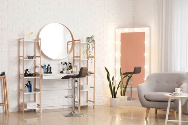 Interior of beauty salon with hairdressing table, armchair and mirrors