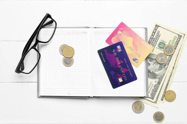 Cuaderno Abierto Con Tarjetas Crédito Dinero Anteojos Sobre Mesa Madera —  Fotos de Stock